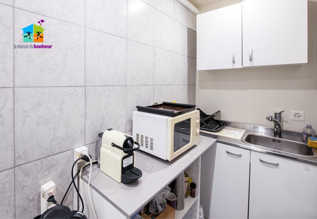 Kitchenette La photo présente la kitchenette, avec le lavabo, les armoires, et un plan de travail avec machine à café et micro-ondes.